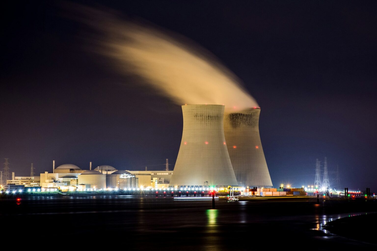 Two nuclear cooling towers emitting steam at night
